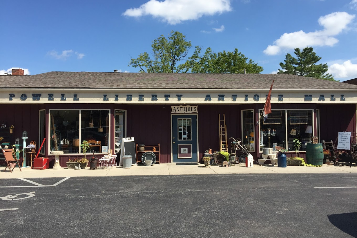 Exterior storefront of Powell Liberty Antique Mall with vintage items displayed on the sidewalk of Delaware, Ohio.