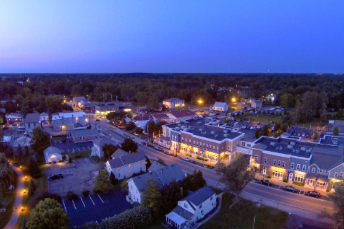 High-angle dusk view of downtown Powell, Ohio, showing illuminated buildings and streetlights along the main road.