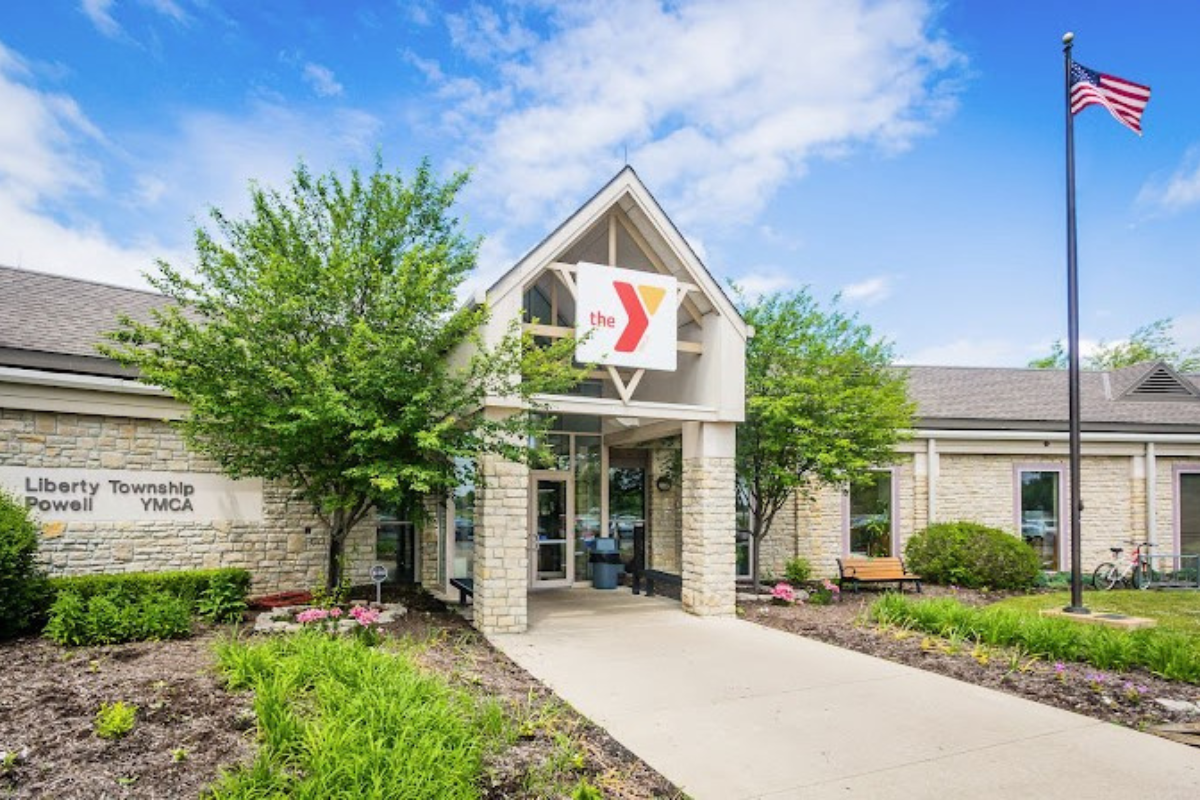 Exterior view of the Liberty Township Powell YMCA building with an American flag and stone siding.