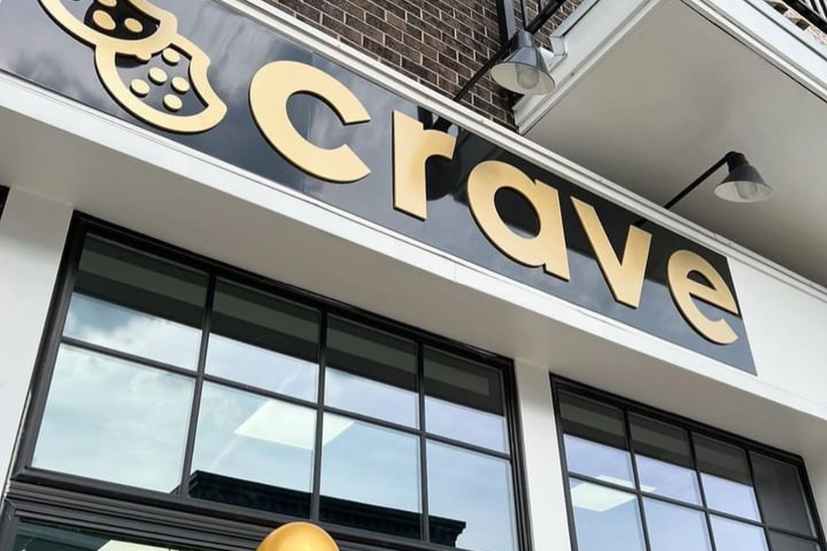 Close-up of the gold Crave Cookies storefront sign at the Evans Farm development.