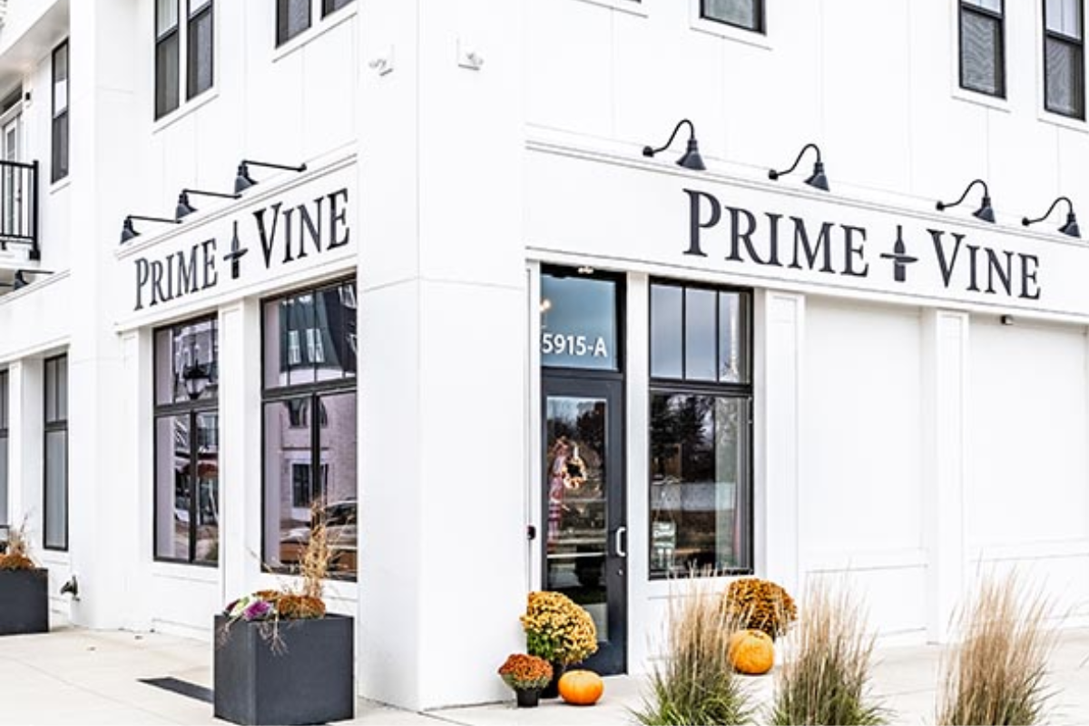 Exterior of Prime and Vine butcher shop and wine bar at Evans Farm, featuring white siding and black signage.