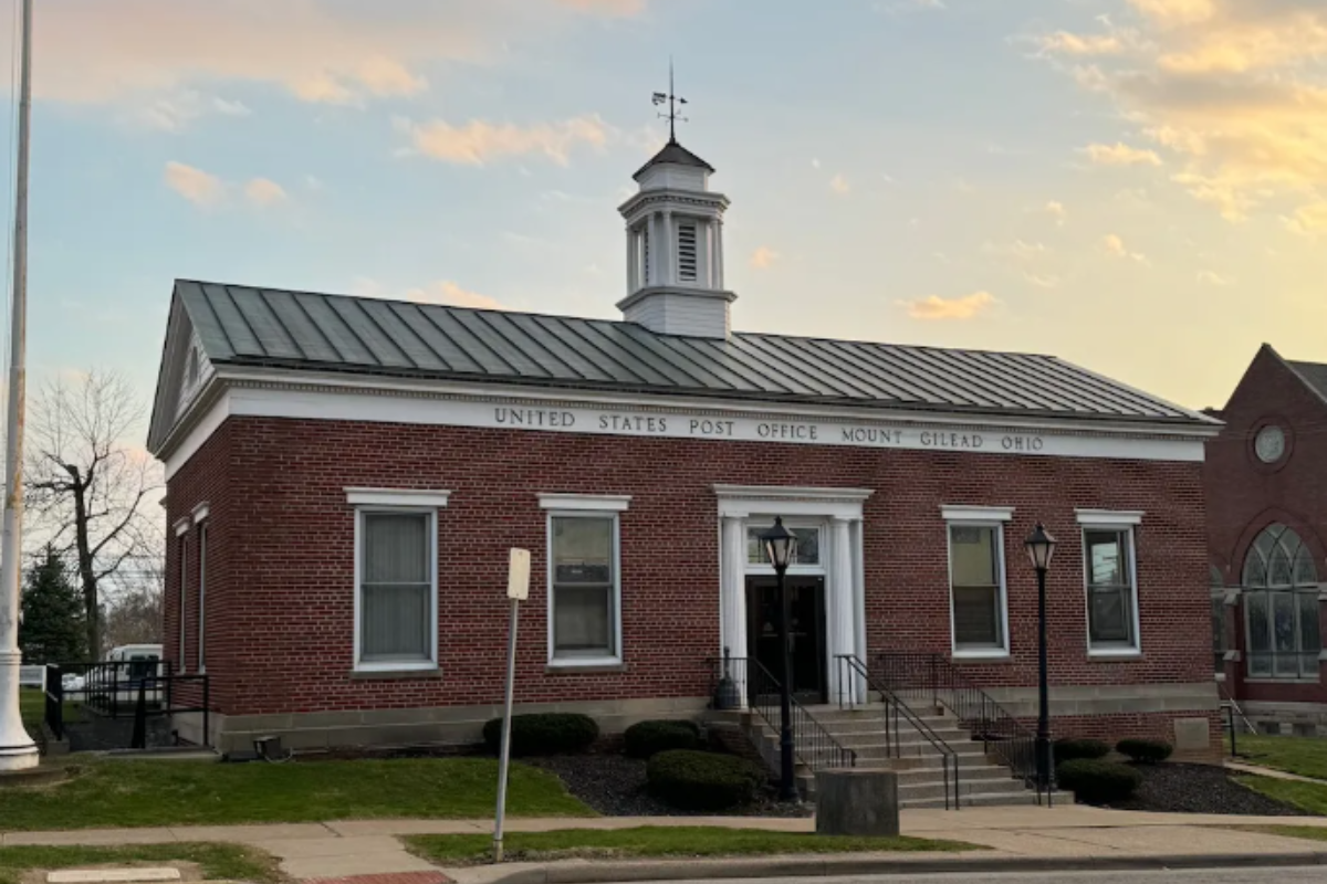 The historic brick United States Post Office building in Mount Gilead, Ohio, featuring a white cupola at sunset.