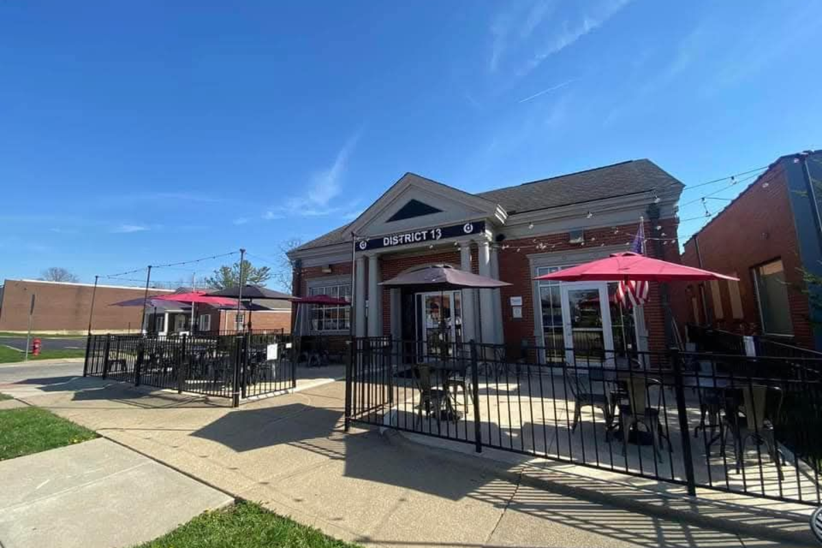 Exterior of District 13 Gastropub featuring an outdoor patio with red and black umbrellas.
