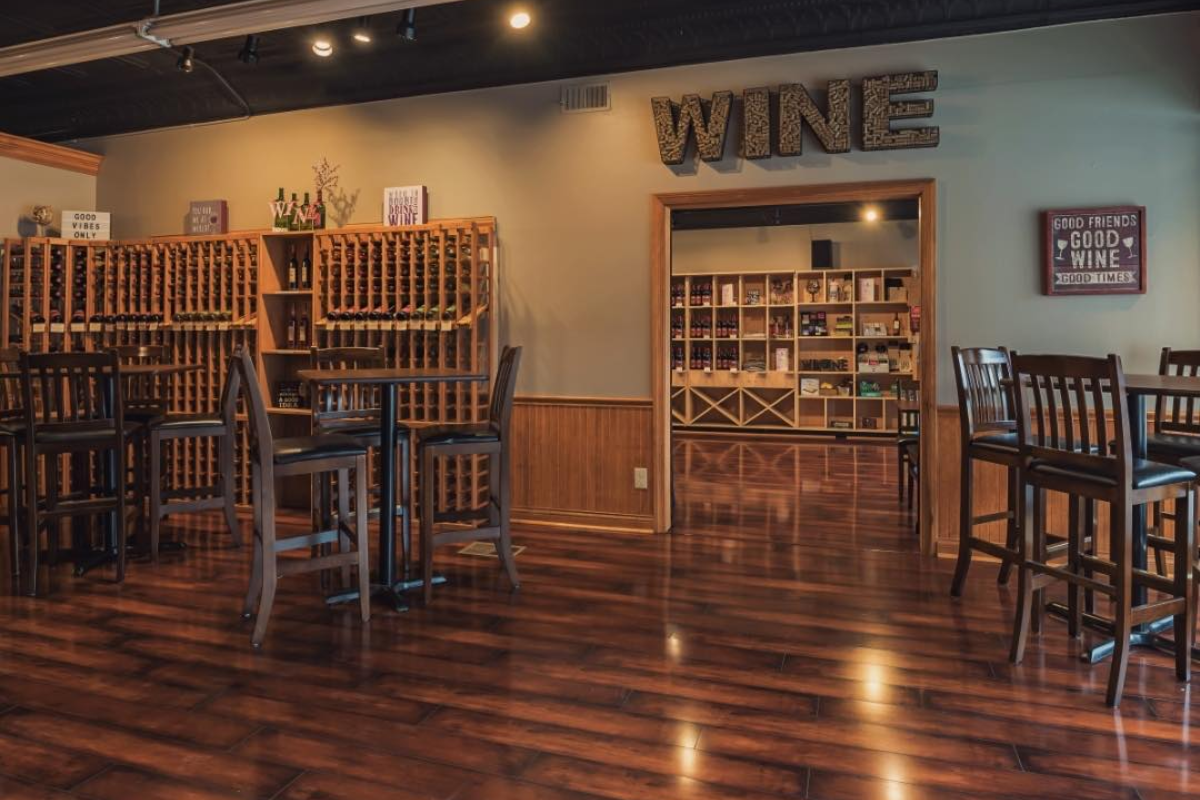 Interior of Good Vibes Winery in Sunbury showing wooden wine racks, tables, and a "WINE" wall sign.