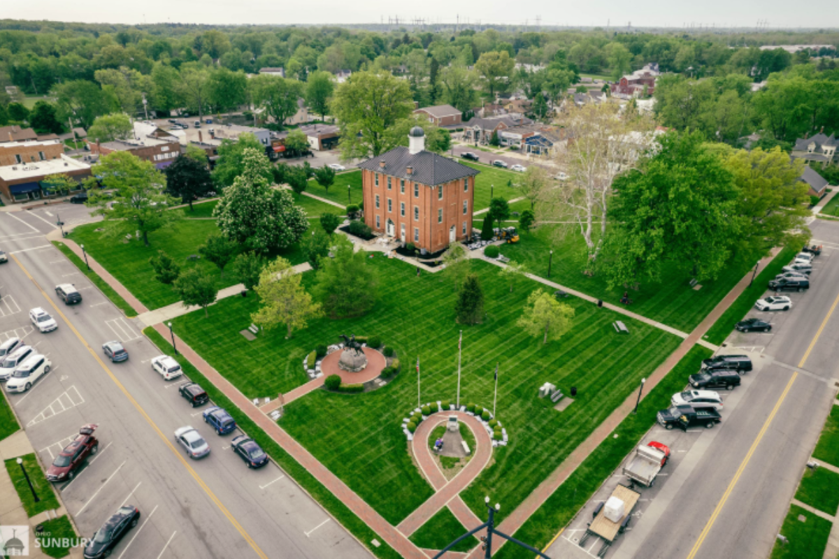 Aerial view of the historic Sunbury Town Square in Ohio featuring the brick town hall and green park space.