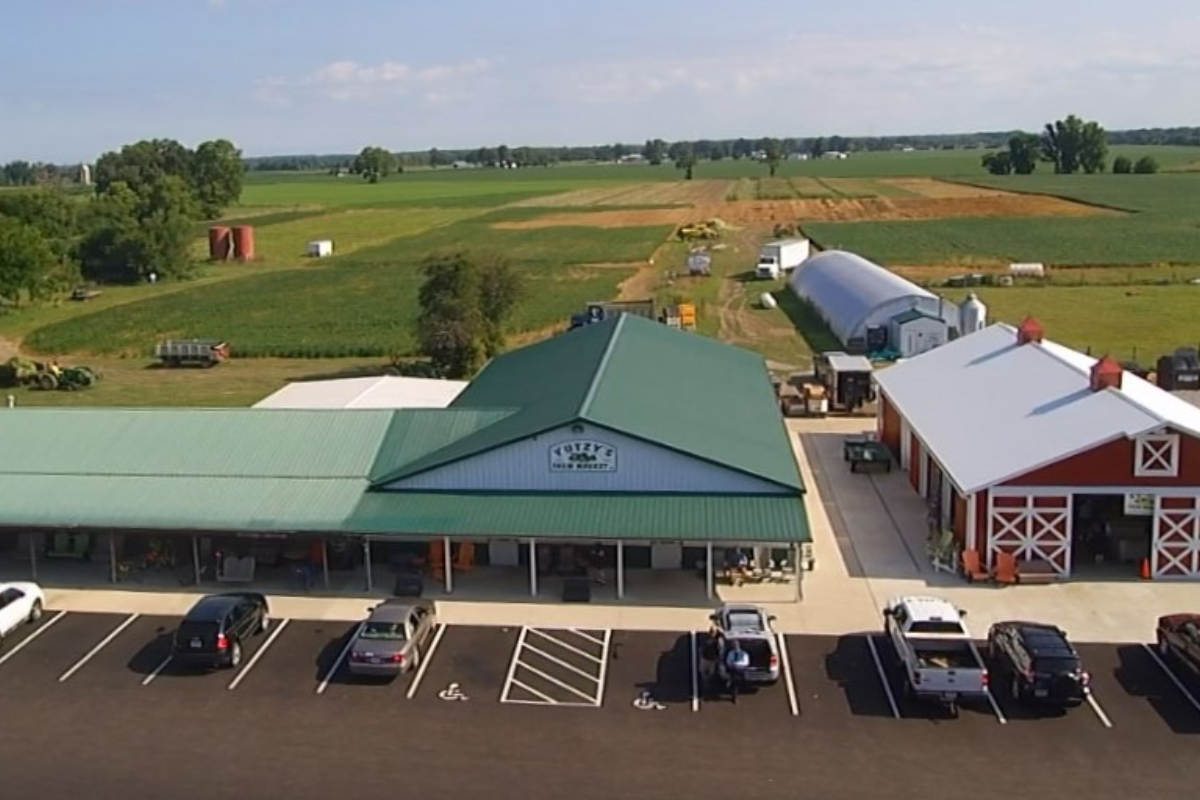 Overhead view of Yutzy's Farm Market building, parking lot, and surrounding green farmland.