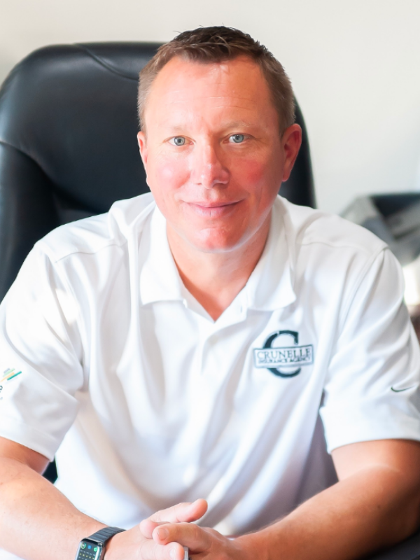 Jonathan Crunelle, top independent insurance agent, smiling in front of an office chair.